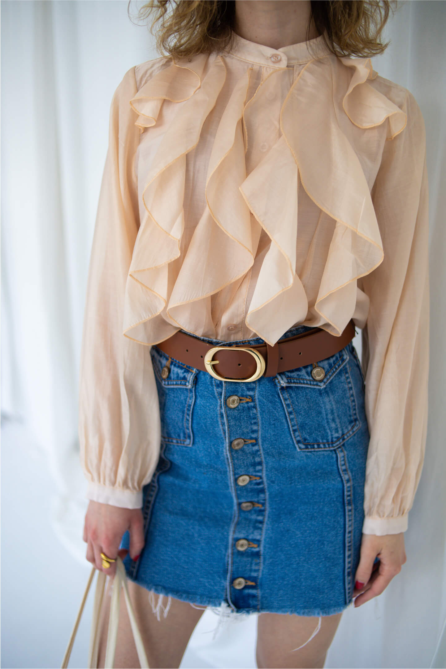 Close-up of a pink ruffled blouse and vintage denim skirt.