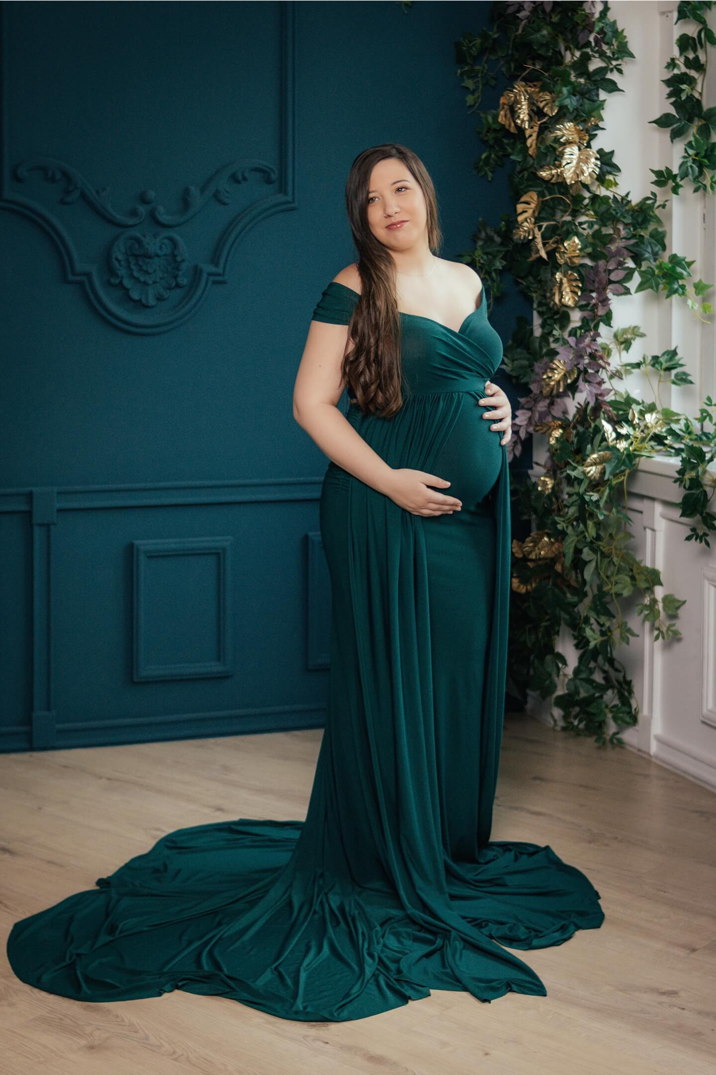 Kismama oldalról fotózva, elegáns zöld ruhában