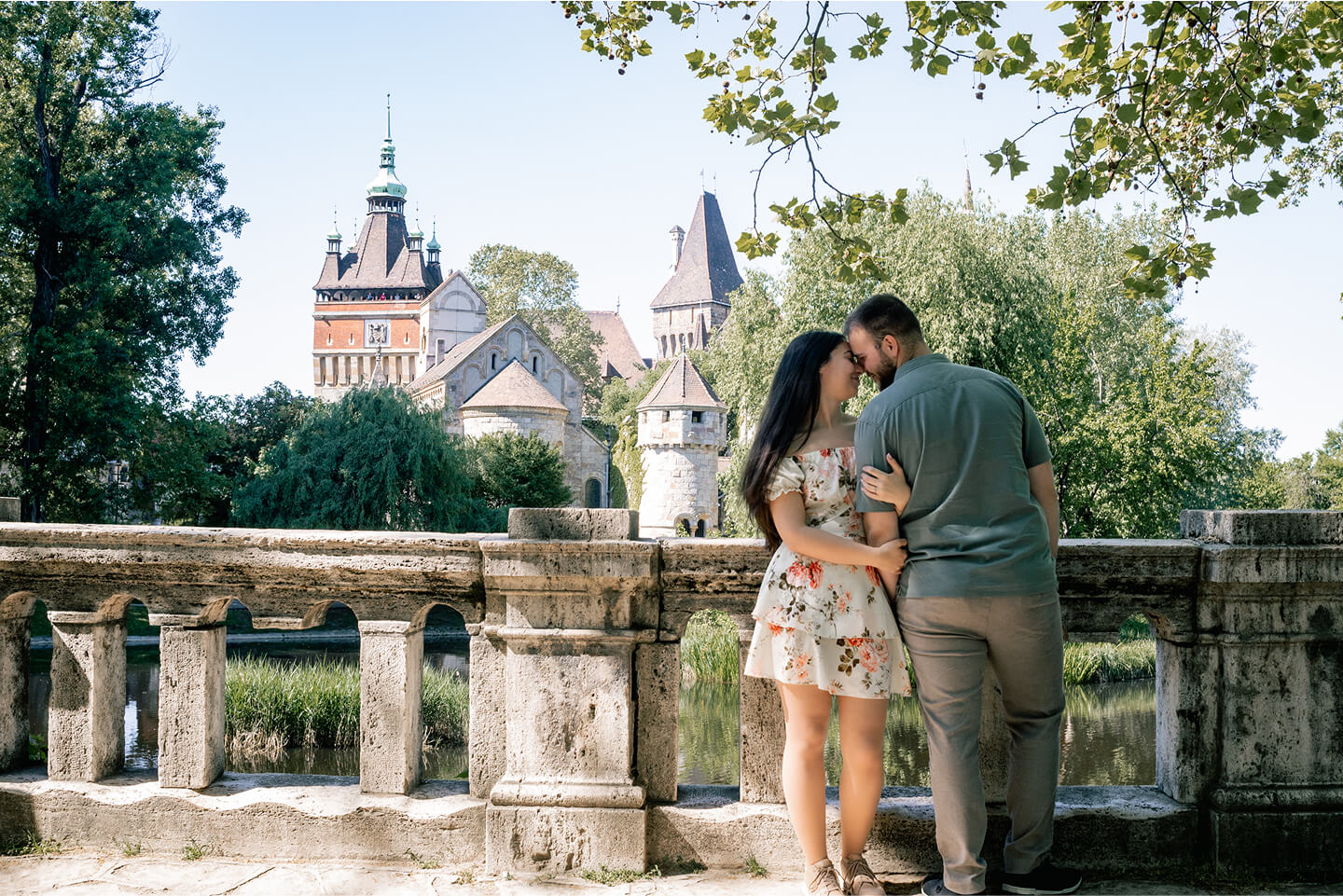 Jegyespár romantikus pózban egy kastélykert kőkorlátjánál.