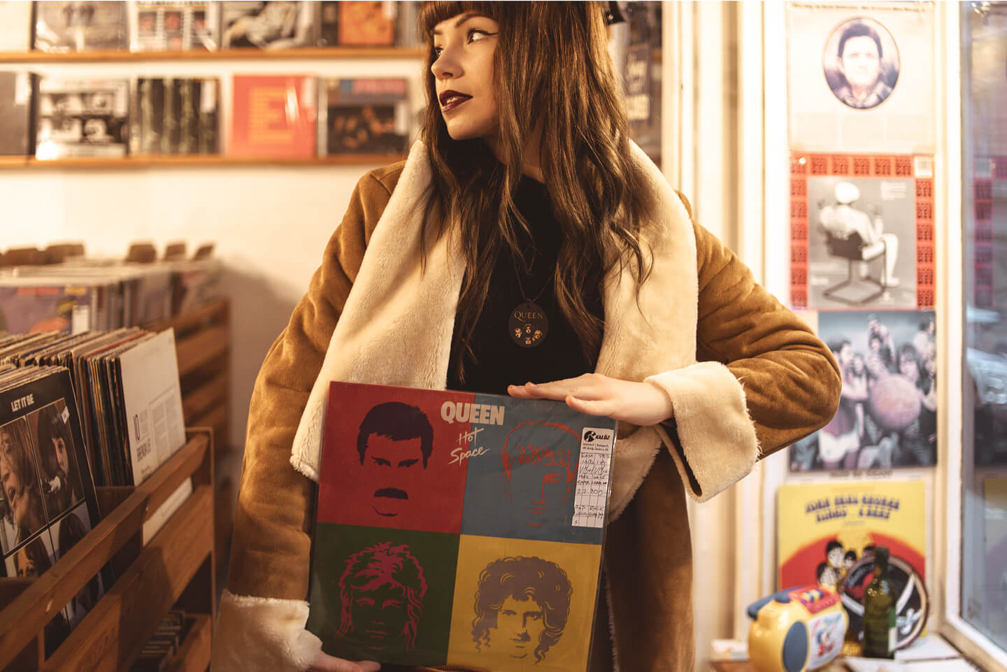 Nő Queen Hot Space lemezt tartva vintage kabátban