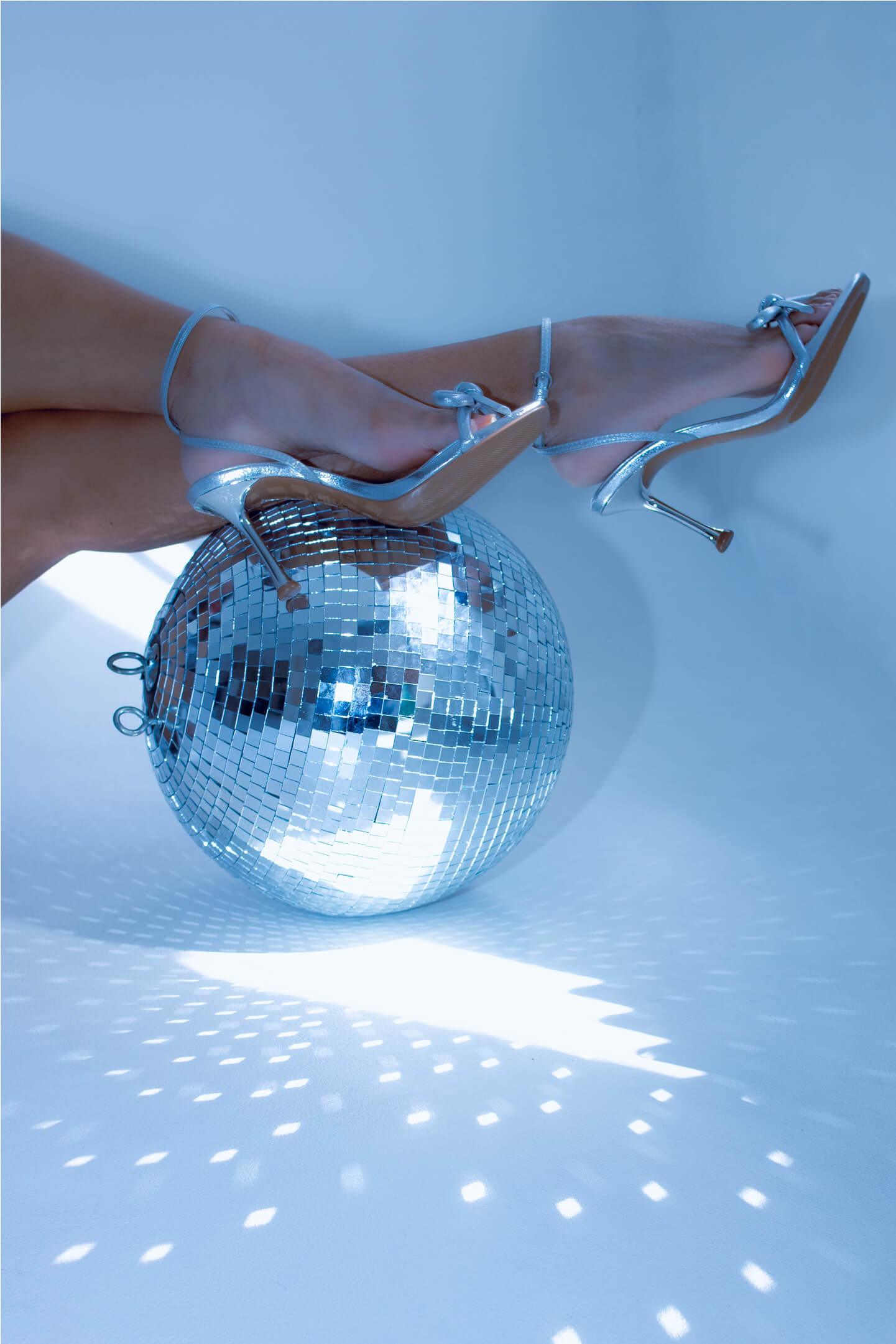 Ezüst tűsarkú cipők disco gömbön, csillogó stúdiófények között